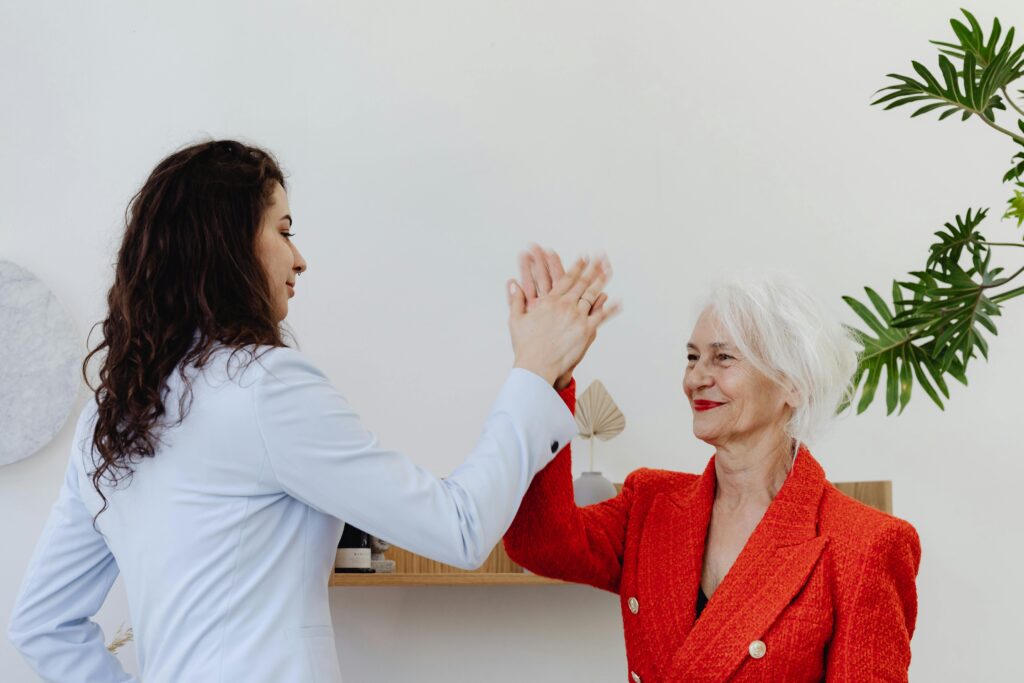 pexels-photo-8528404-8528404 Two businesswomen share a high five in a modern office environment, symbolizing teamwork and success.